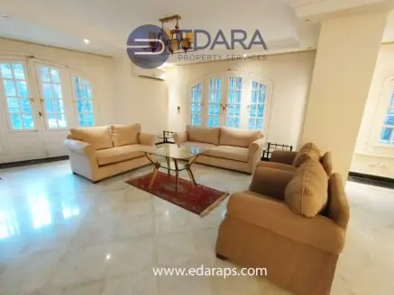 Living room featuring beige sofas arranged around a glass coffee table on a marble floor.