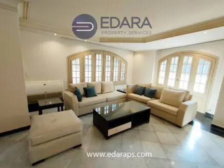 Modern living room featuring a light-colored sofa set with cushions and a black coffee table.