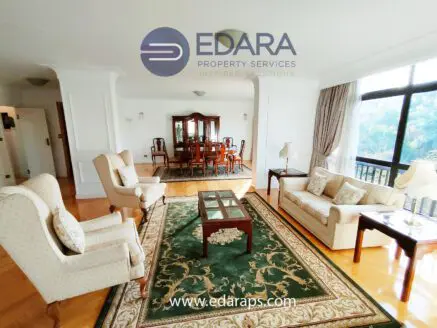 Spacious living room featuring a coffee table, two armchairs, and a sofa with a patterned rug.