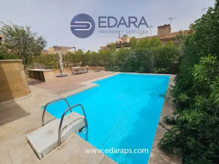 Swimming pool with clear blue water and surrounding greenery in a residential outdoor area.