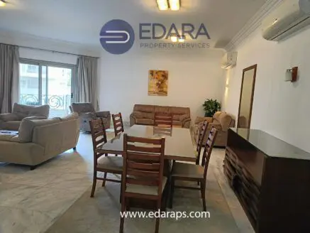 Spacious living room and dining area featuring a table and chairs, with a sofa set and air conditioning units.