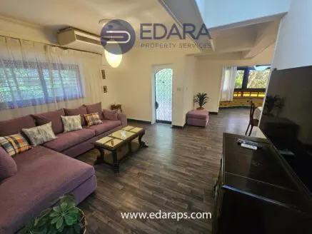 Interior view of a living room featuring a purple sofa, coffee table, and television.
