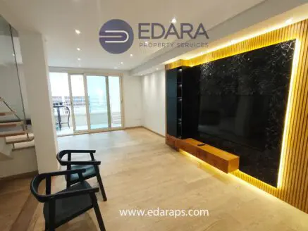 Contemporary living room featuring a wall-mounted TV and wooden accents in a bright space.