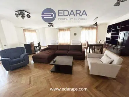 Spacious living room featuring a sectional sofa, armchair, and dining table with chairs.