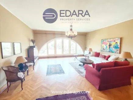 Spacious living room featuring arched windows, a red sofa, and decorative items.