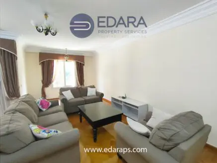 Interior view of a living room featuring light-colored sofas and a coffee table with a decorative pillow.