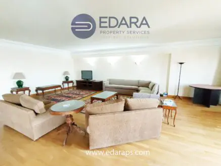 Living room featuring a large sofa, coffee table, TV unit, and decorative lamps in a neutral color scheme.