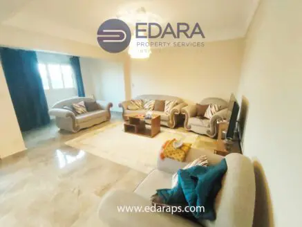 Living room featuring light-colored sofas arranged around a coffee table with a rug on the floor.