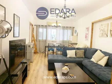 Living room featuring a blue sectional sofa, a coffee table, and a dining area with chairs and a table.