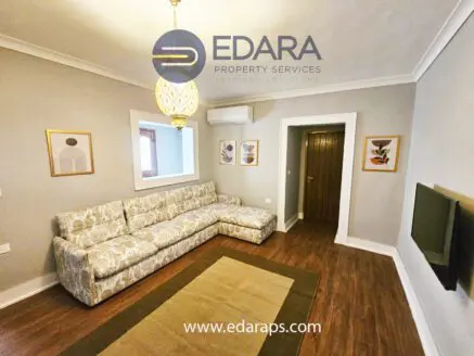 Living room featuring a patterned sofa, wall art, and a television mounted on the wall.