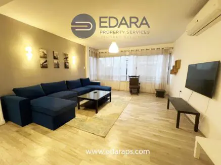 Living room featuring a blue sectional sofa, coffee table, and wall-mounted TV in a modern interior design.