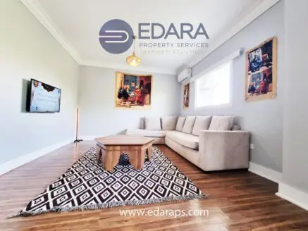 Modern living room featuring a beige sofa, wooden coffee table, and decorative rug on the floor.