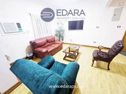 Living room featuring a brown leather sofa, an armchair, and a coffee table on wooden flooring.