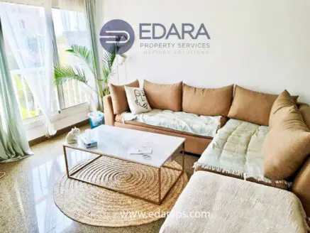 Contemporary living room featuring a beige sectional sofa and a glass coffee table on a round jute rug.