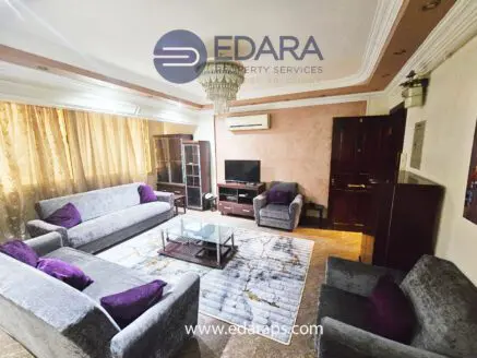 Living room featuring gray sofas, a coffee table, and a television in a well-lit space.