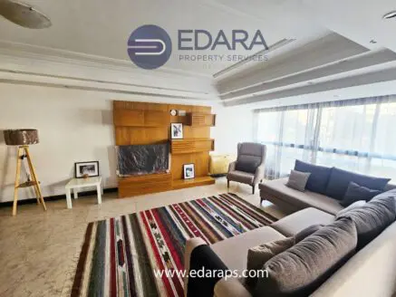 Contemporary living room featuring a gray sofa, a colorful rug, and wooden wall decor.