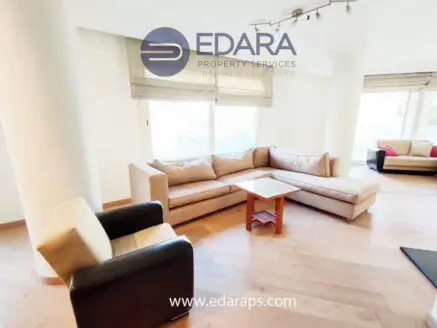 Contemporary living room featuring a beige sectional sofa and a wooden coffee table with a black armchair.