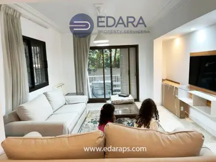 Bright living room featuring a light-colored sofa and a television mounted on the wall.