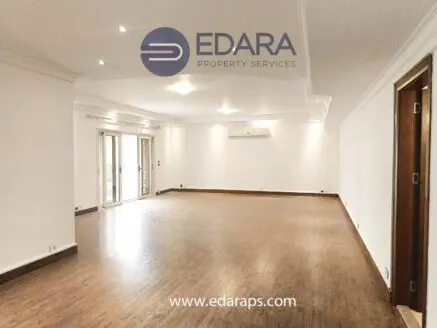 Empty room featuring wooden flooring and white walls, with large windows allowing natural light.