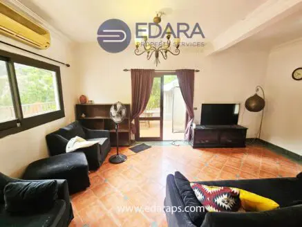 Living room featuring a black sofa, television, and decorative elements in a neutral color scheme.