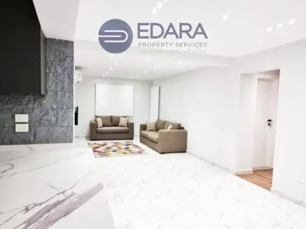Contemporary living room with two sofas, colorful rug, and marble flooring.