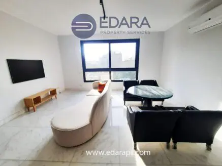 Contemporary living room featuring a curved sofa, coffee table, and black armchairs in a bright space.