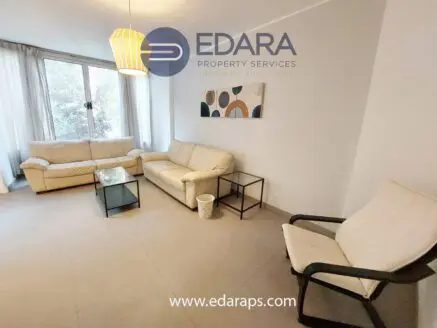 Living room featuring a white sofa set, glass coffee table, and an armchair in a neutral color scheme.