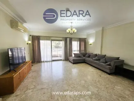 Spacious living room featuring a gray sectional sofa and a flat-screen television on a wooden console.