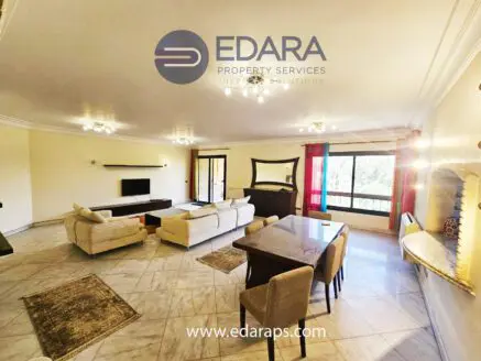 Bright living room with a dining table, sofas, and large windows allowing natural light.