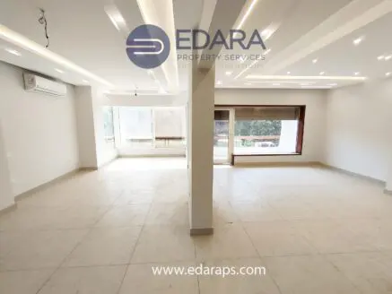 Bright, spacious empty room with large windows and modern ceiling design in a neutral color scheme.