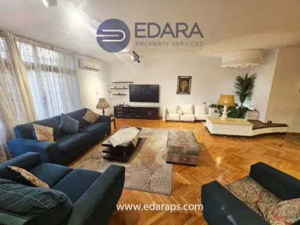 Living room featuring blue sofas, a coffee table, and a television on a wooden stand.