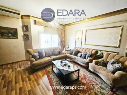 Living room featuring a beige sofa set, decorative pillows, and a coffee table with ornaments.
