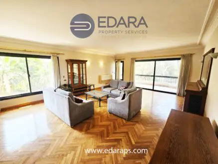 Living room featuring large windows, a coffee table, and gray sofas in a well-lit space.