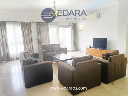 Spacious living room featuring a brown sofa set, coffee table, and television against a light-colored wall.