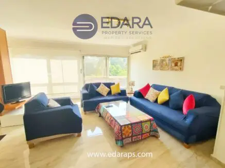 Living room featuring blue sofas with colorful cushions and a patterned coffee table.
