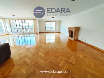 Bright living room featuring polished wooden flooring and large windows for natural light.