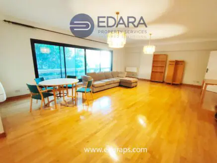 Spacious living room featuring a sofa, dining table with chairs, and wooden flooring.