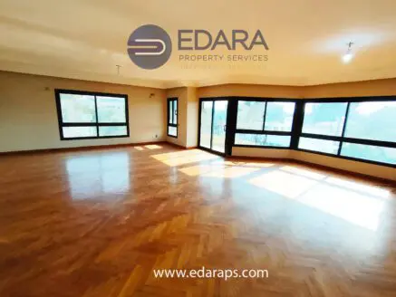Bright interior space featuring large windows and wooden flooring in a residential setting.