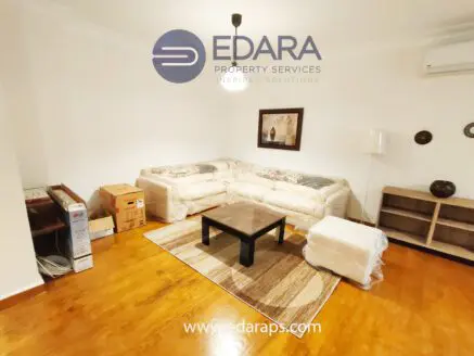 Living room featuring a beige sofa, coffee table, and wooden flooring with decorative elements.