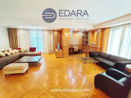 Spacious living room featuring a sectional sofa, coffee table, and a desk area with natural light.
