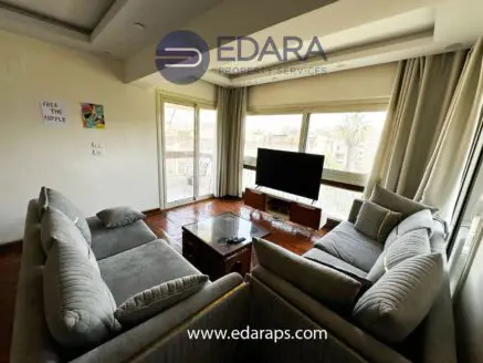 Modern living room featuring a grey sofa set and a television on a wooden stand.