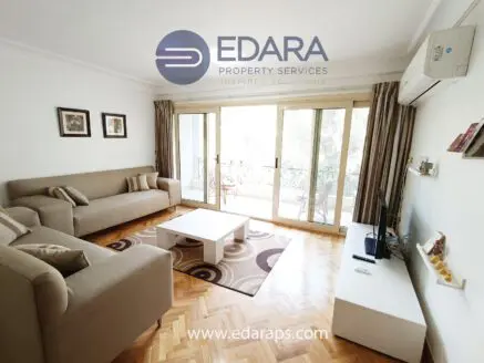Bright living room featuring two sofas, a coffee table, and a television unit against a light-colored wall.
