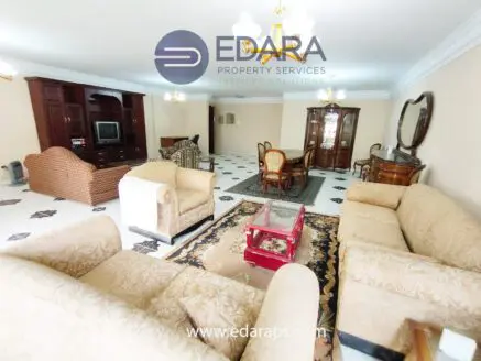 Spacious living room featuring beige sofas, a wooden cabinet, and a dining table with chairs.