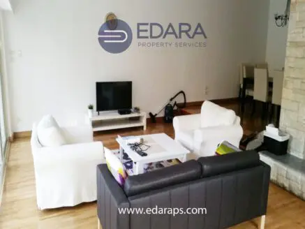 Living room featuring two white sofas, a black couch, and a television on a white stand.
