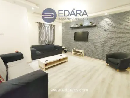 Contemporary living room with gray brick wall, sofa, coffee table, and television.