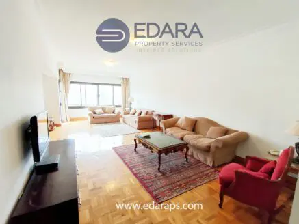 Spacious living room featuring beige sofas and a wooden coffee table in a well-lit environment.