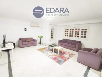 Living room featuring two purple sofas, a coffee table, and a colorful area rug on a marble floor.