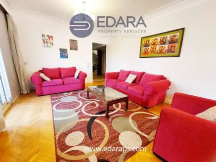 Living room featuring two pink sofas, a glass coffee table, and a decorative area rug with circular patterns.