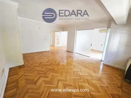 Empty room featuring herringbone parquet flooring and sliding doors leading to another space.