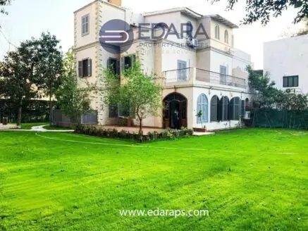 Two-story residential building with a green lawn and trees surrounding it.